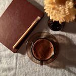 Cozy flat lay of coffee, journal, and flower on table, creating a warm and inviting atmosphere.